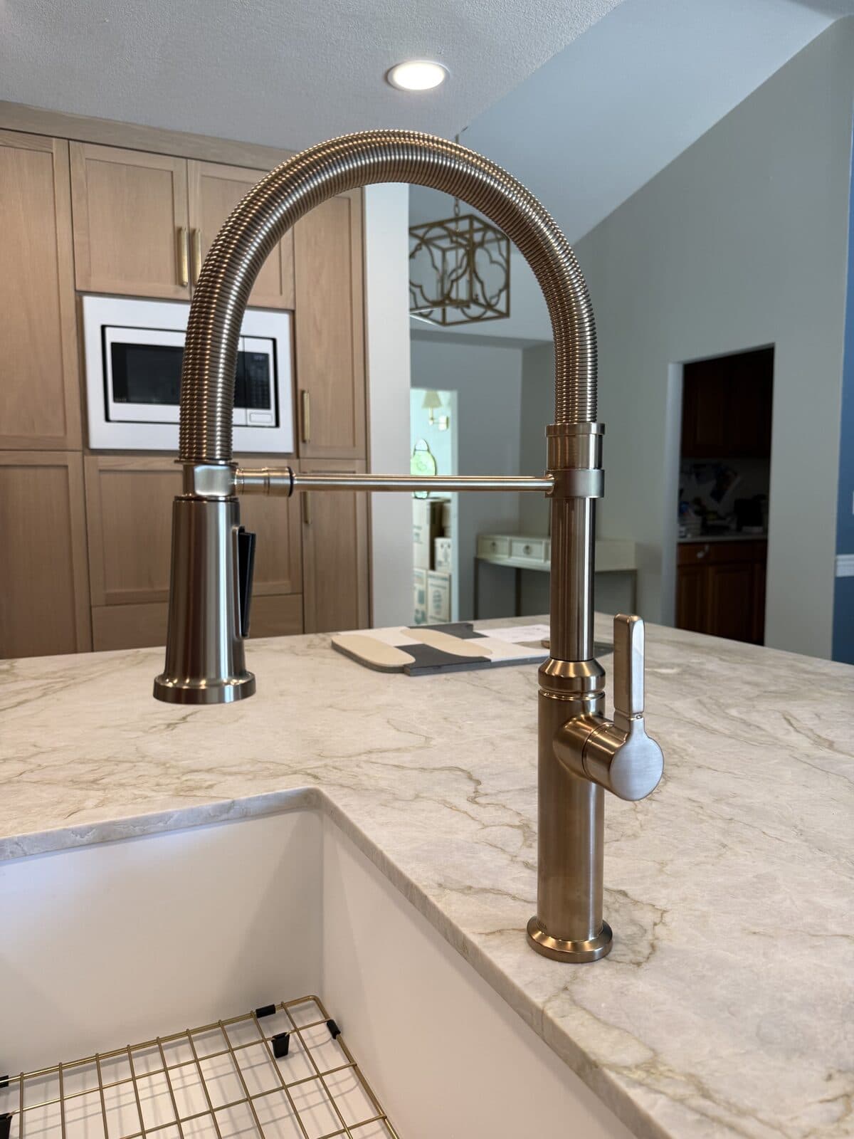 Gooseneck kitchen faucet mounted over a farmhouse sink on a stone countertop