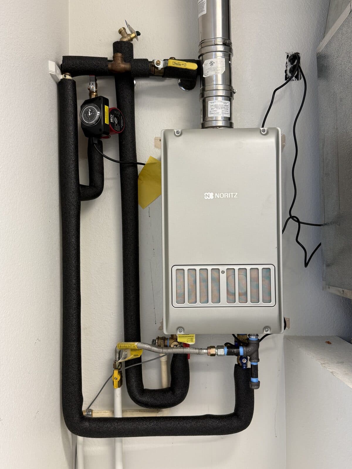 Wall mounted tankless water heater with new gas and water line runs